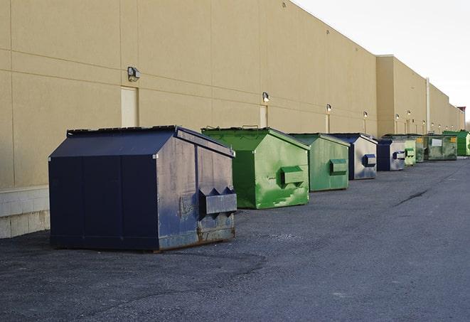 a waste management truck unloading into a construction dumpster in Ardmore